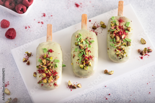 Ice cream sticks with white chocolate, fruit, pistachios and colored sugar on a white background.