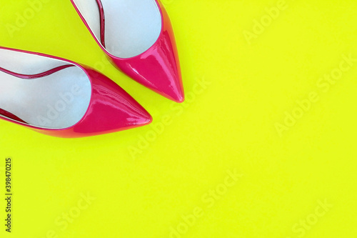 Women's pink patent leather shoes on a bright yellow background.