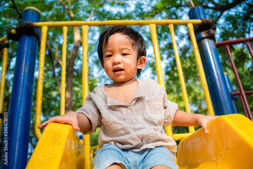 Toddler preschool boy playing slider outdoor park