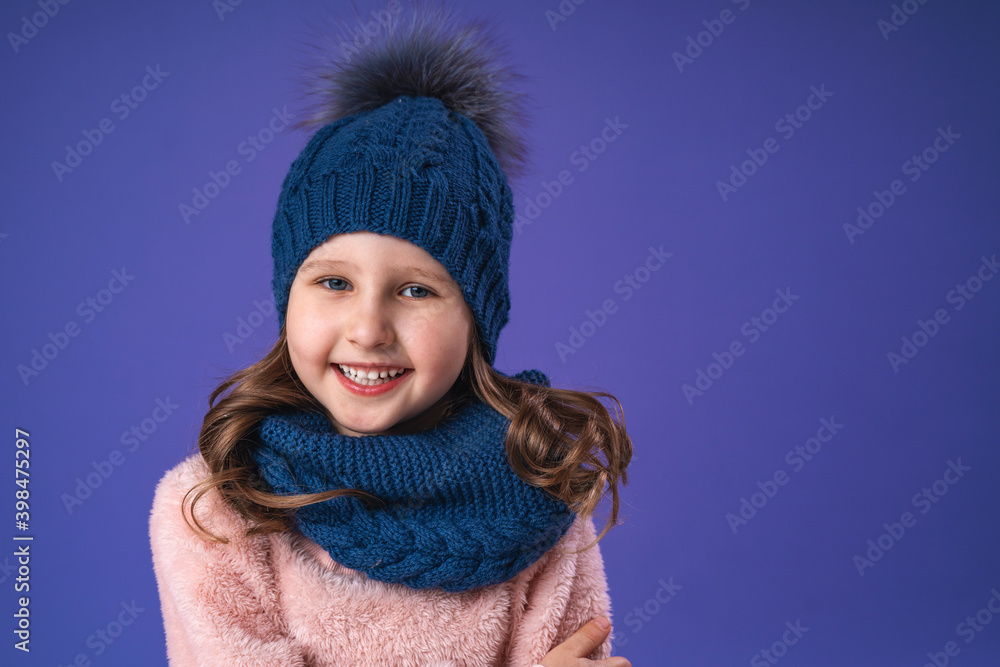 Portrait of a little girl 5 years old with blonde hair in a blue hat and scarf Portrait of a little girl 5 years old with blonde hair in a blue hat and scarf