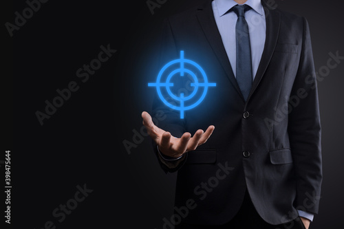 Targeting concept with businessman hand holding target icon dartboard sketch on chalkboard. Objective target and investment goal concept.