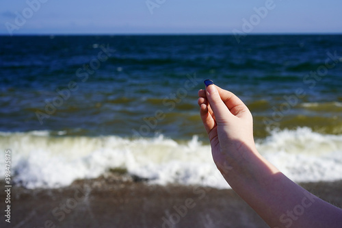 Child's hand with sea glass on the sea background.