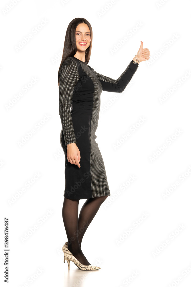 Profile of young beautiful smiling woman in a short tight dress, showing thumbs up Profile of young beautiful smiling woman in a short tight dress, showing thumbs up