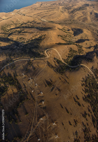 Aerial drone panorama shot of mountain area, windmills, the long and winding road through the mountains. Southern region, sands, desert 
