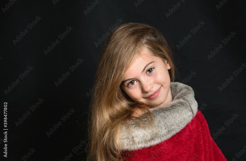 Teenage girl in a red fur coat in the studio on a black background. Teenage girl in a red fur coat in the studio on a black background.