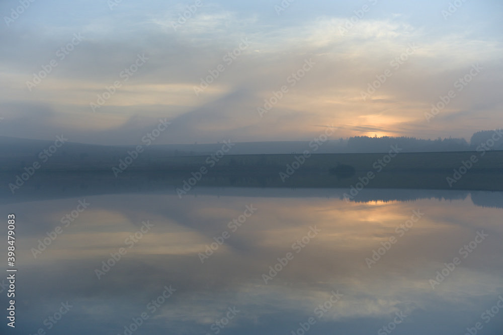 Abstract cloud formations at sunset reflected in still reservoir water Abstract cloud formations at sunset reflected in still reservoir water