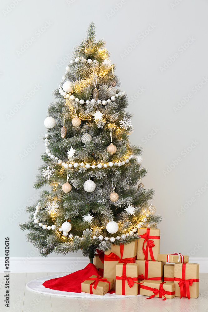 Decorated Christmas tree with red skirt and gifts indoors