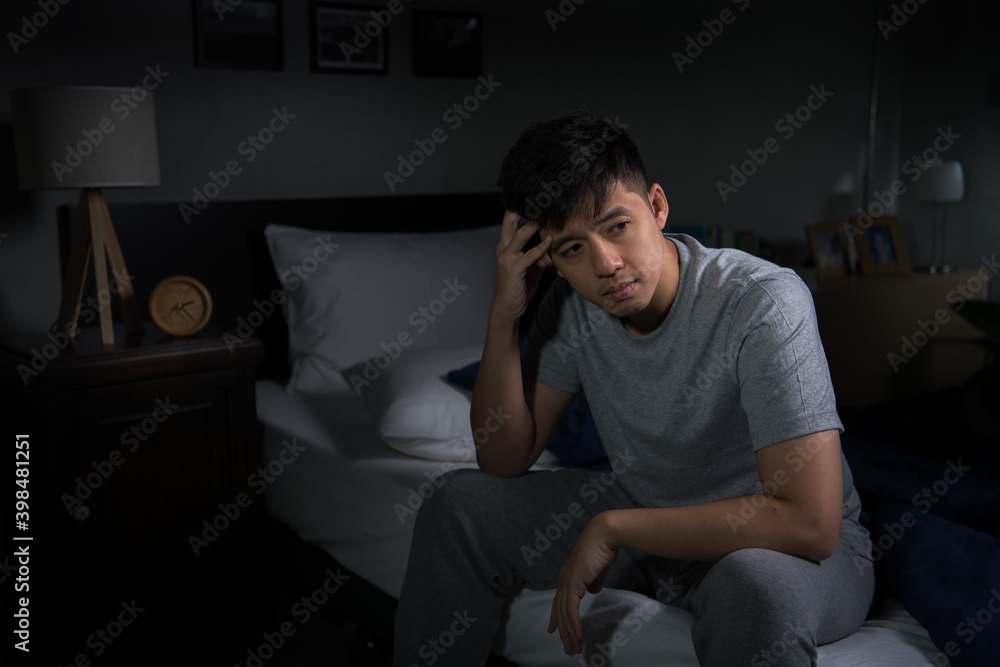 Fototapeta premium Depressed young man suffering from insomnia sitting in bed..
