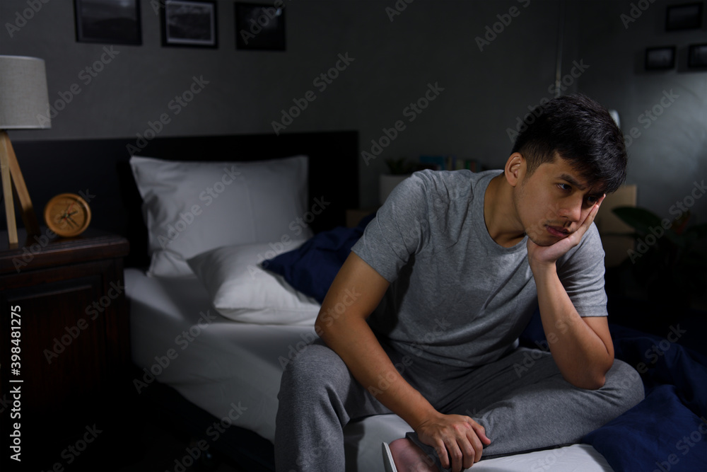 Depressed young man suffering from insomnia sitting in bed.. Depressed young man suffering from insomnia sitting in bed..