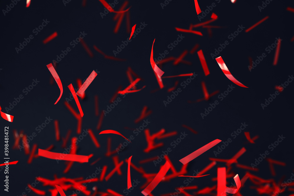 Shiny red confetti falling down on dark blue background