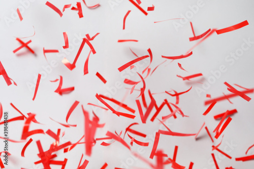 Shiny red confetti falling down on light grey background