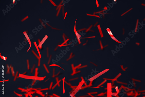 Shiny red confetti falling down on dark blue background