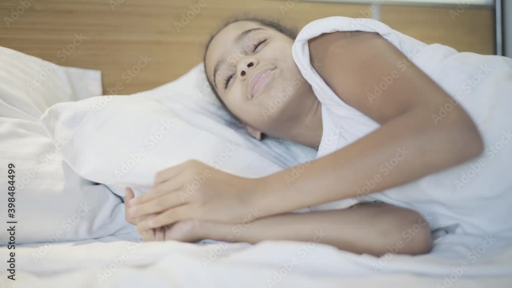 Close-up of relaxed African American cute girl waking up in the morning in bed. Portrait of pretty teenager opening and rubbing eyes. Relaxation and leisure concept. Close-up of relaxed African American cute girl waking up in the morning in bed. Portrait of pretty teenager opening and rubbing eyes. Relaxation and leisure concept.