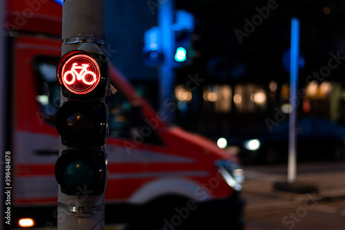 Gefahren im Verkehr für Radfahrer veranschaulicht durch den Kontrast einer roten Ampel und dem Straßenverkehr im Hintergrund photo