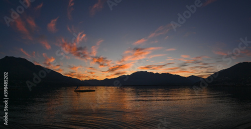 Suggestivo tramonto sul lago in autunno  con nuvole colorate di rosa  rosso e arancione. Immagine molto bella. 