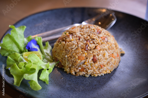 fried rice Thai in the dark dish with blue flower and spoon set on the wooden table