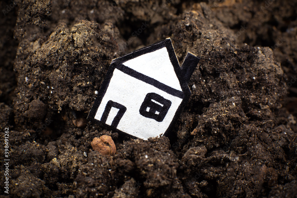 House in the soil, falling into a crack in the earth. Сoncept of earthquake and loss of a house. Сredit debts. House in the soil, falling into a crack in the earth. Сoncept of earthquake and loss of a house. Сredit debts.