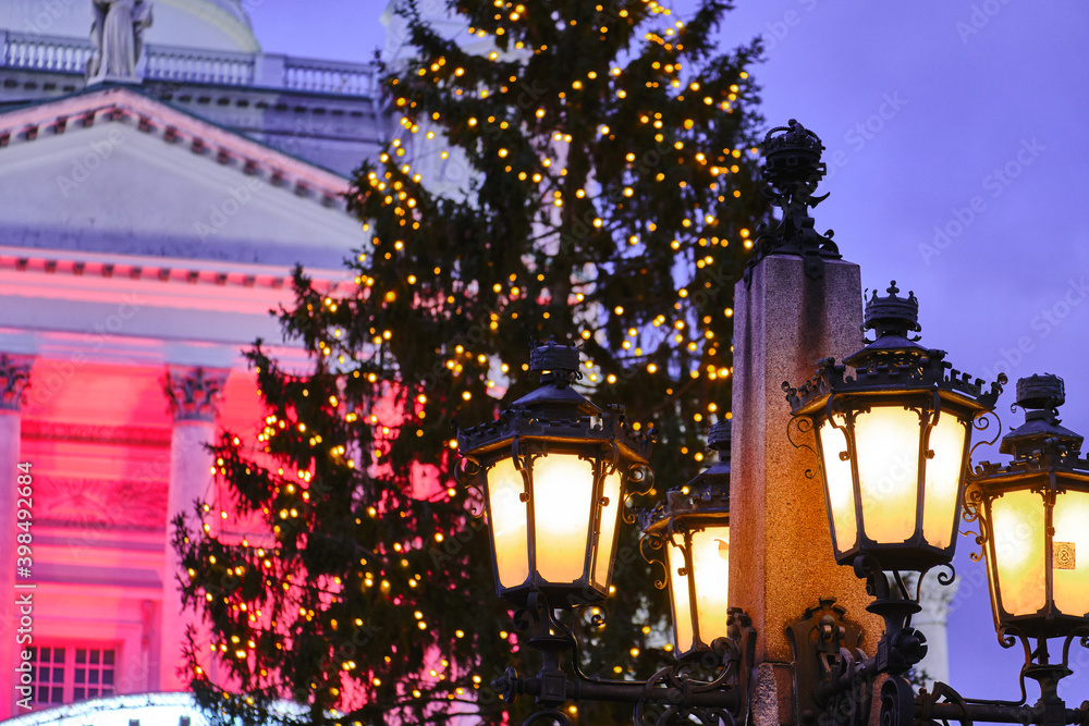 The classic old street lamp. The Christmas tree and Helsinki Cathedral on the blurred background.