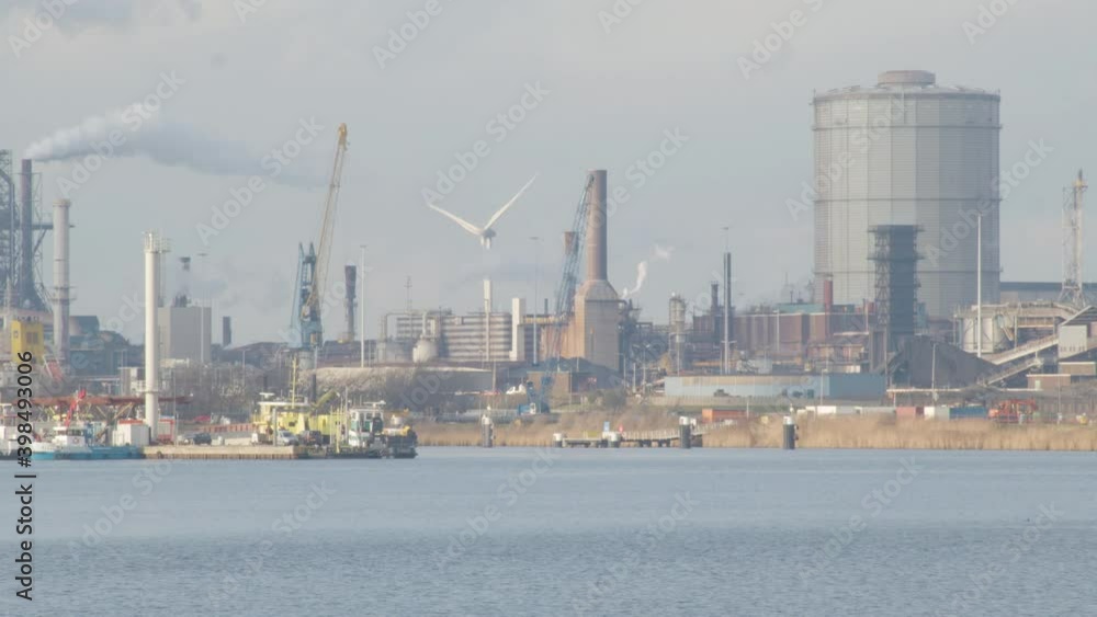 Windmill standing on a polluting industrial terrain located near river Windmill standing on a polluting industrial terrain located near river
