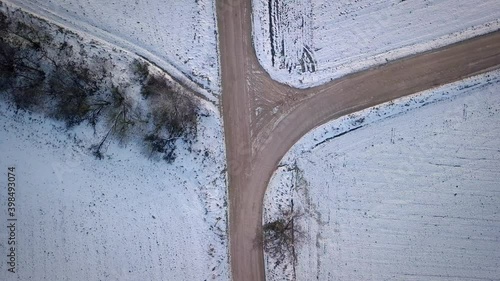 Intersect Country Road Surrounded By Snow Covered Fields During Winter In Latvia, Europe. - Aerial Ascendinfg Shot photo