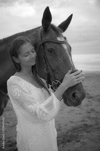 Monochrome. Portrait of beautiful woman and horse. Caucasian woman hugging and stroking horse. Black-white photo. Love to animals. Beach in Bali, Indonesia