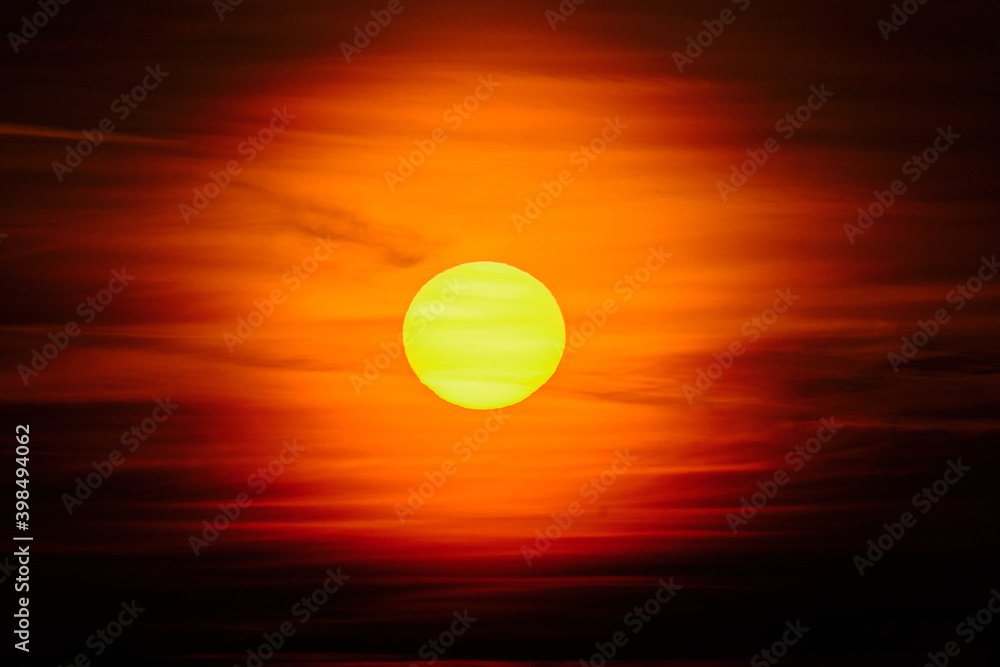 Close-up sunset through the clouds. Big orange sun.