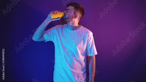 Man with a beard drinks water from an iron can on a purple background