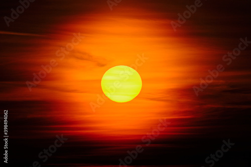 Obraz na płótnie Close-up sunset through the clouds. Big orange sun. w salonie