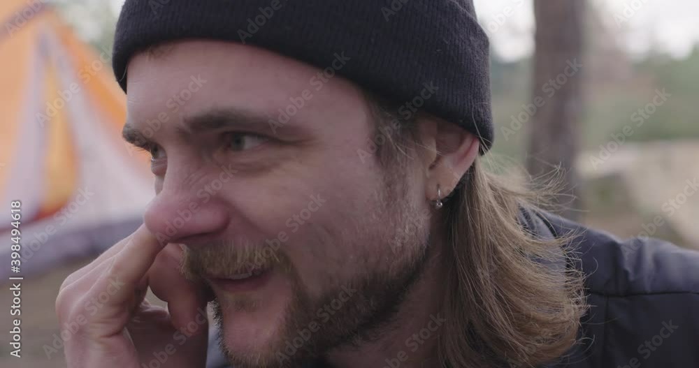 Young tourist man picks his nose, notices something off to the side and stops. Young tourist man picks his nose, notices something off to the side and stops.