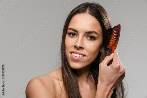 Beautiful shirtless happy girl smiling and combing her hair