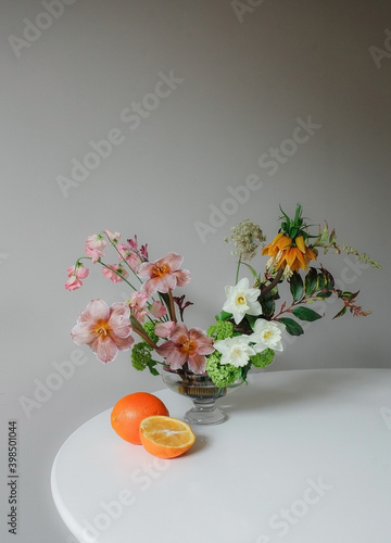 Flower arrangement with orange on white table