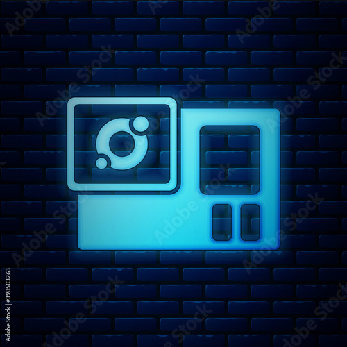 Glowing neon Action extreme camera icon isolated on brick wall background. Video camera equipment for filming extreme sports.  Vector.
