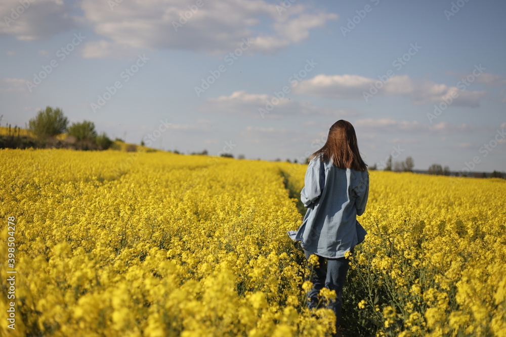 young beautiful woman in a field with yellow blooming rapeseed. girl in yellow floral field, rapeseed plantation, summer vacation concept young beautiful woman in a field with yellow blooming rapeseed. girl in yellow floral field, rapeseed plantation, summer vacation concept