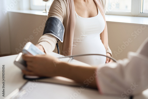 Doctor measuring blood pressure of her pregnant patient. High quality photo