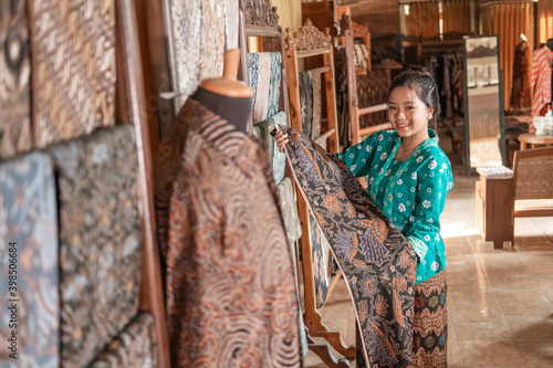 portrait of young customer service in traditional indonesian batik store