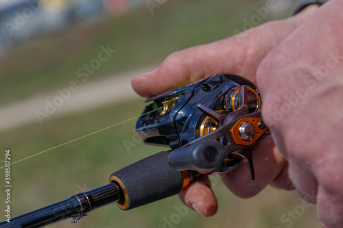 hand with spinning and reel on the evening summer lake. Fishing on the lake at sunset. Fishing background.