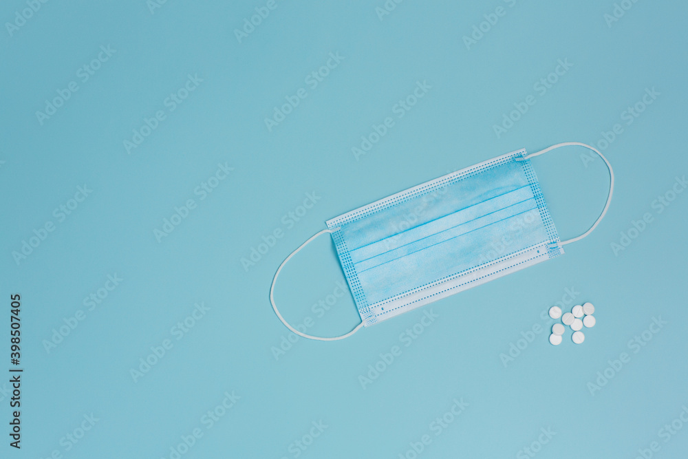 White pills and medical mask on a blue background. Medicine. Copy space. White pills and medical mask on a blue background. Medicine. Copy space.