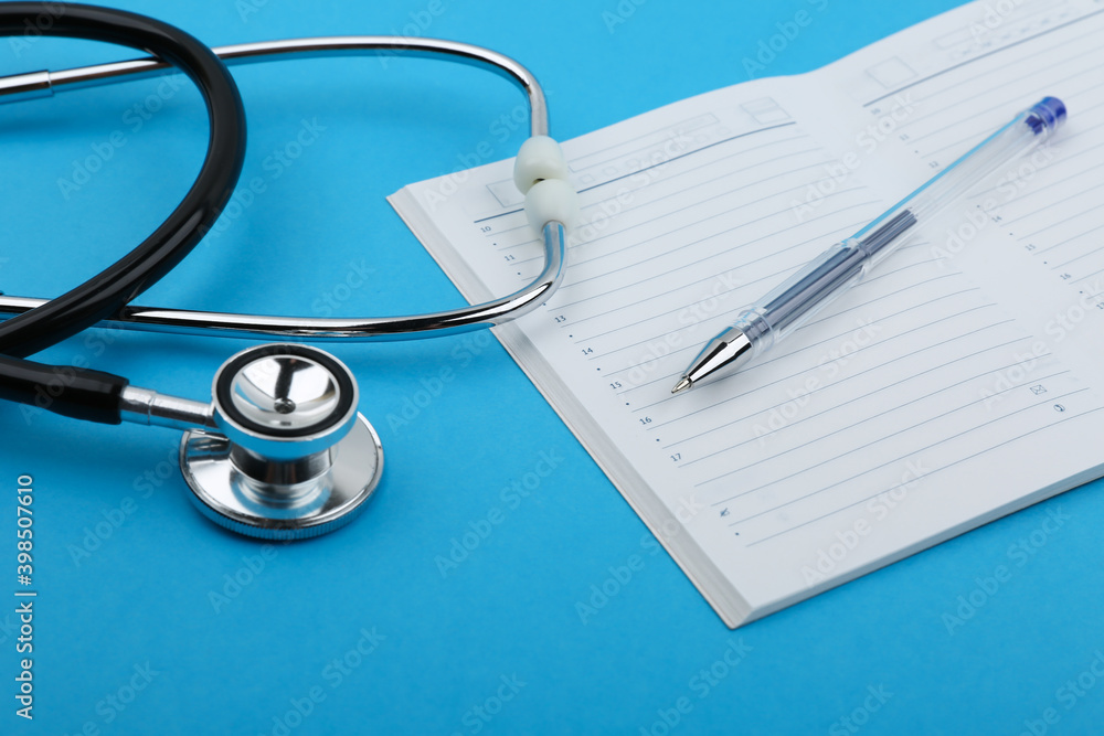 the concept of doctor's schedule, scheduled doctor's appointment. stethoscope, pen and daily planner on blue background top view. the concept of doctor's schedule, scheduled doctor's appointment. stethoscope, pen and daily planner on blue background top view.