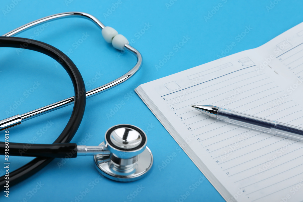 the concept of doctor's schedule, scheduled doctor's appointment. stethoscope, pen and daily planner on blue background top view. the concept of doctor's schedule, scheduled doctor's appointment. stethoscope, pen and daily planner on blue background top view.