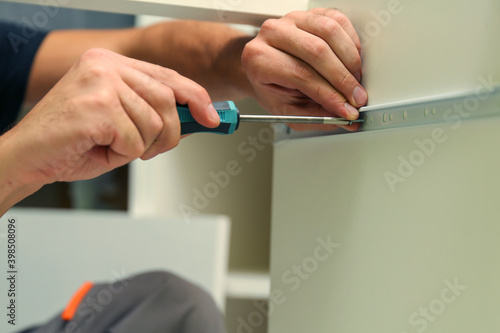 furniture assembler assembles a kitchen cabinet. men hands install new furniture close-up. furniture assembling service concept