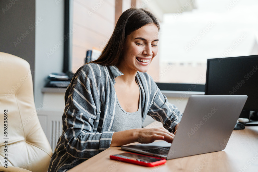 Charming happy woman smiling while working with laptop at home Charming happy woman smiling while working with laptop at home