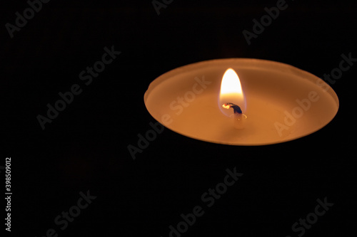 candle light in the dark with copy space. single isolated tea light against dark background
