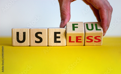 Useful or useless symbol. Male hand turns cubes and changes the word 'useless' to 'useful'. Beautiful yellow table, white background. Business and useful or useless concept. Copy space. photo