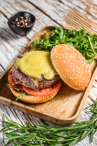 Big cheeseburger with beef, tomato, cheese and arugula.  wooden background. Top view