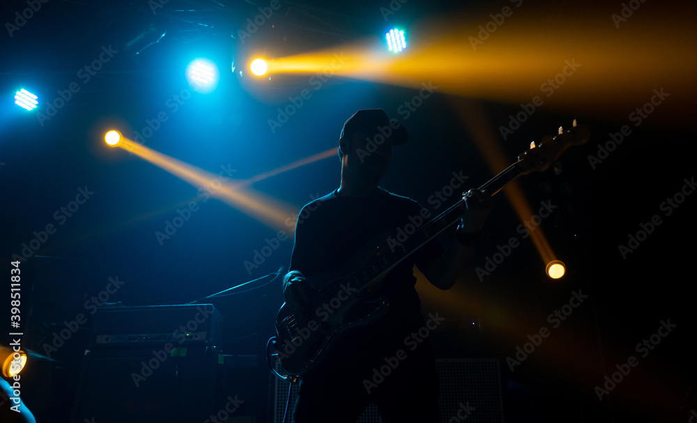 Fototapeta premium Silhouette of man play bass on Rock concert stage with colorful lighting.