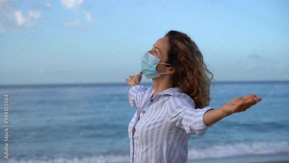 Happy woman wearing medical mask outdoor against blue sky background Happy woman wearing medical mask outdoor against blue sky background