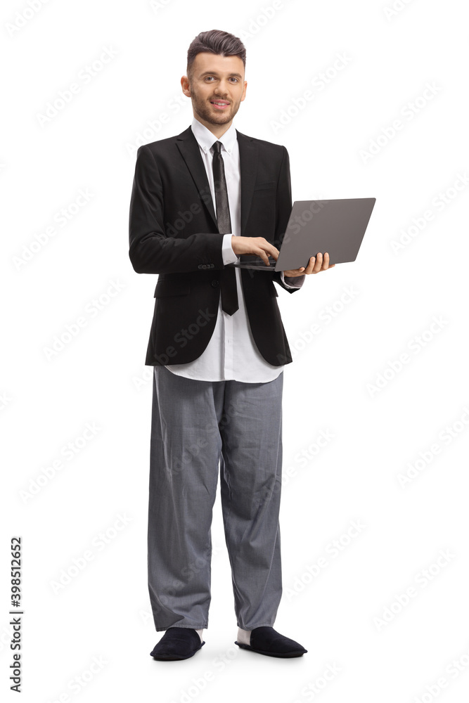 Full length portrait of a businessman in a suit and pajamas standing and working on a laptop Full length portrait of a businessman in a suit and pajamas standing and working on a laptop