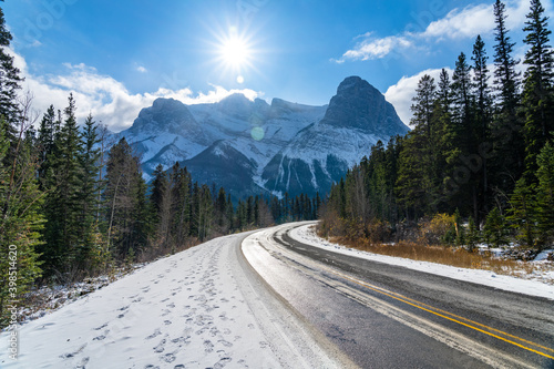 Three Sisters Parkway (Highway 742) in early winter season sunny day morning. Clear blue sky, snow capped Mount Lawrence Grassi in background. Canmore, AB, Canada.