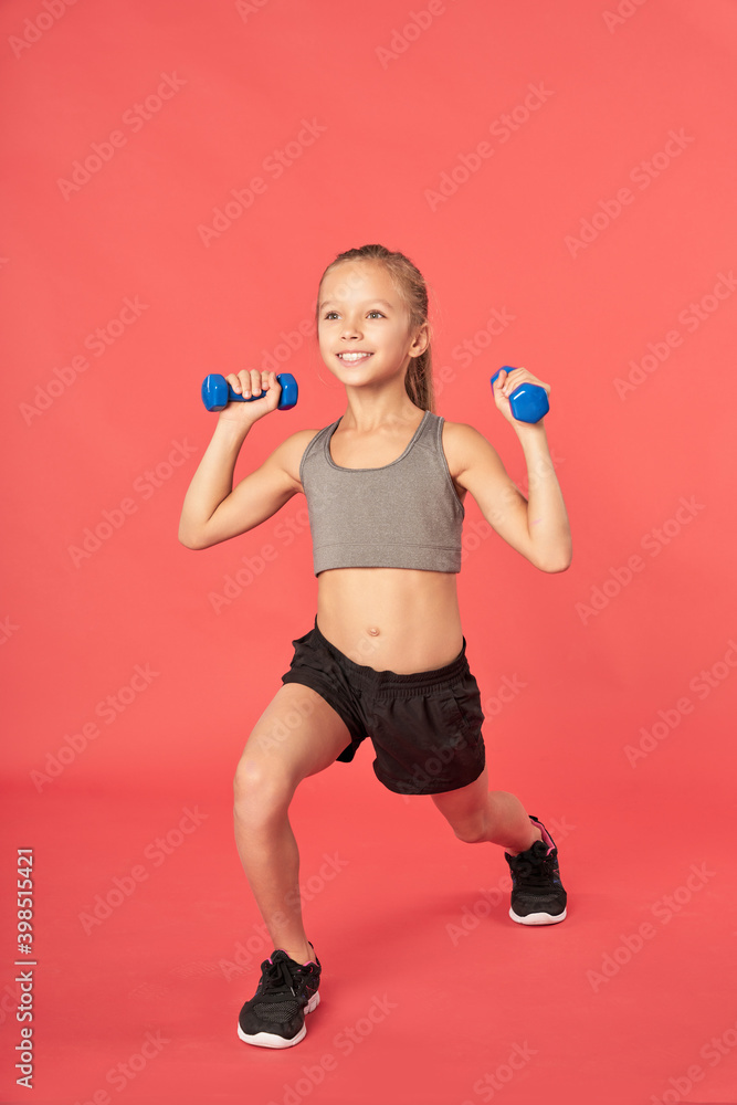 Cheerful sporty girl working out with dumbbells Cheerful sporty girl working out with dumbbells