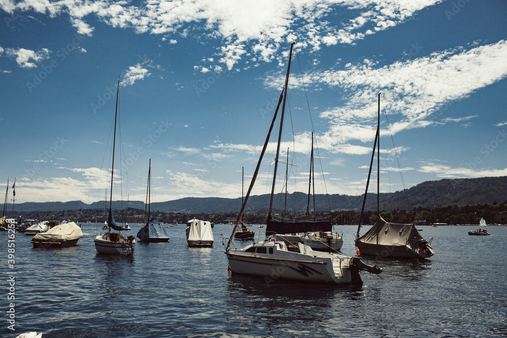 Lake Zurich on a sunny, hot summer day, some clouds in the sky, anchored boats in the bay